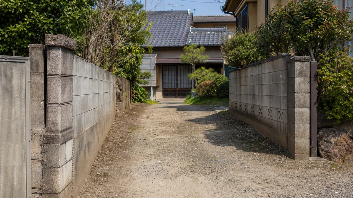 細い私道の奥にある日本の古い住宅のイメージ